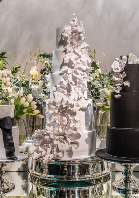 Luxurious multi-tier wedding cake surrounded by elegant floral arrangements
